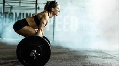 Woman doing a deadlift with an Olympic barbell