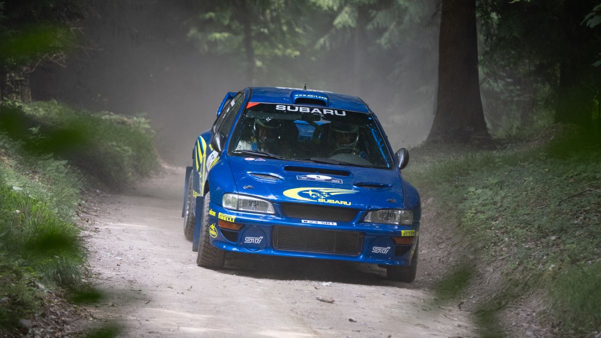 A rally car turning the corner of a race track at Goodwood