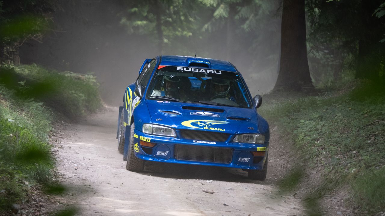 A rally car turning the corner of a race track at Goodwood