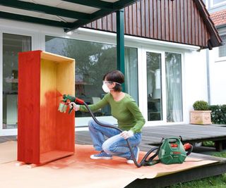 Bosch Home and Garden 603207170 Electric Paint Spray System being used on furniture