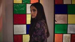 Sofia Boutella looking back cryptically in front of a stained glass window in Argylle.