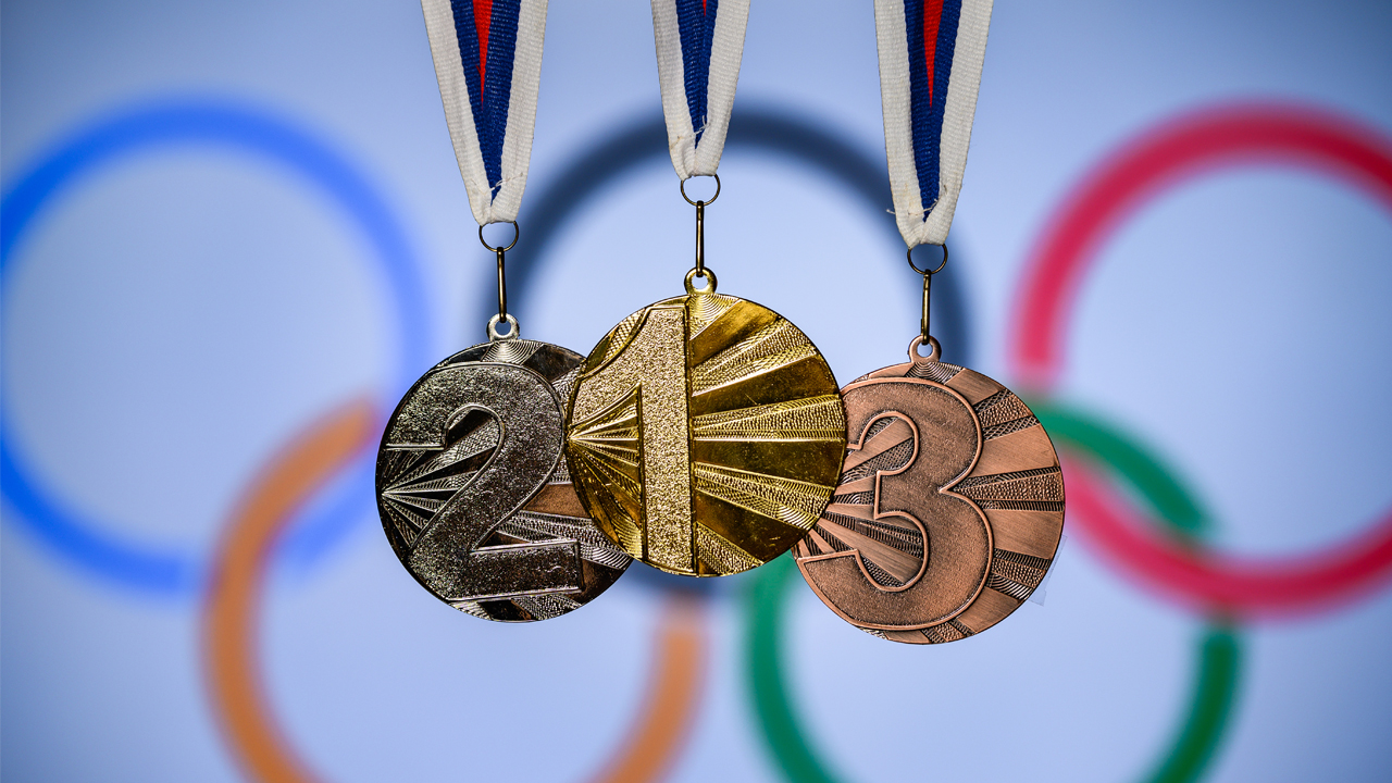 Gold, silver and bronze medals in front of the Olympics rings logo