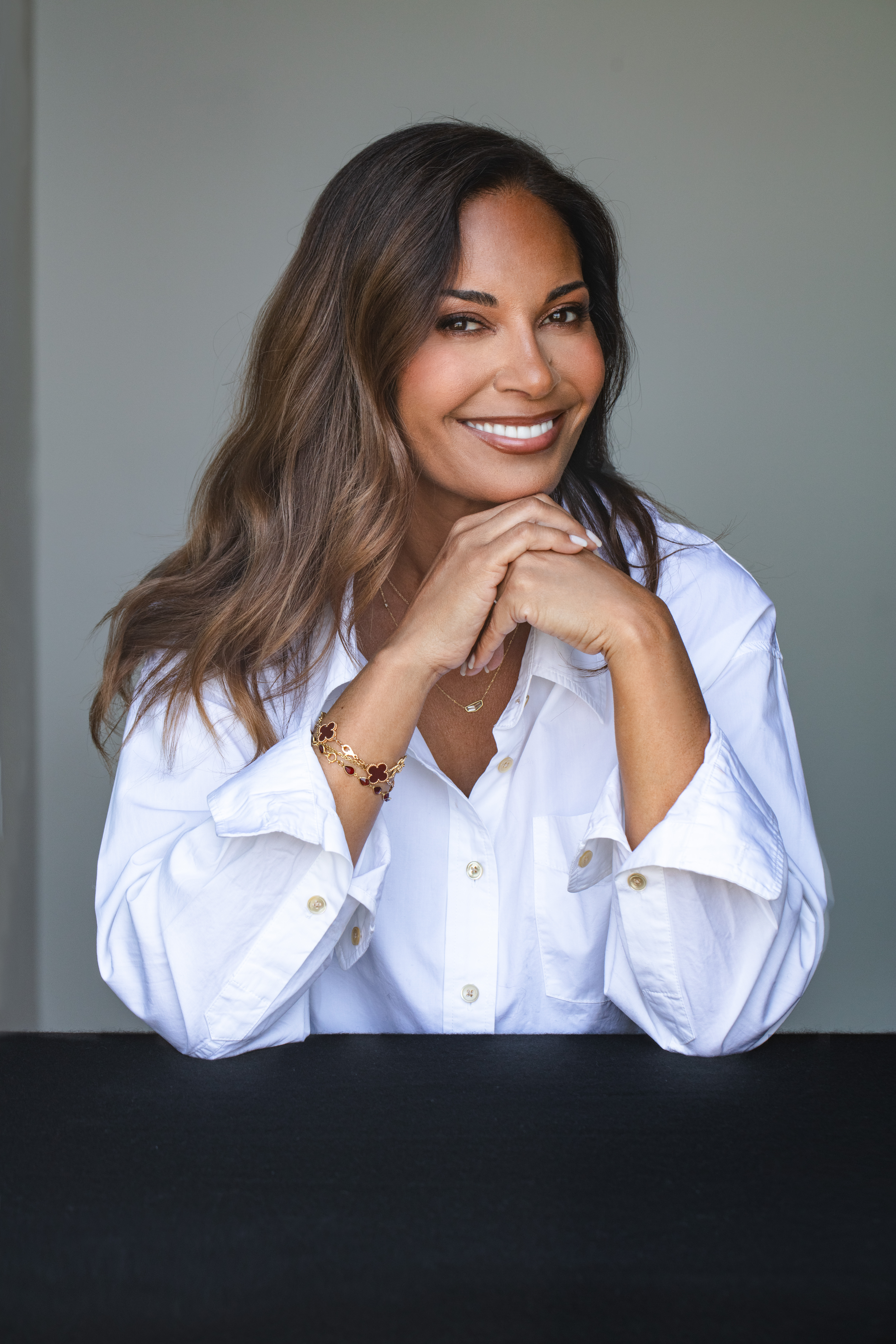 director salli richardson whitfield poses while sitting and resting her chin on her hands wearing a white button down