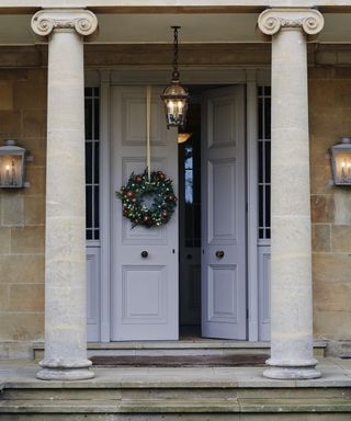 Christmas porch decor ideas with a grey double doors, sandstone columns and a wreath