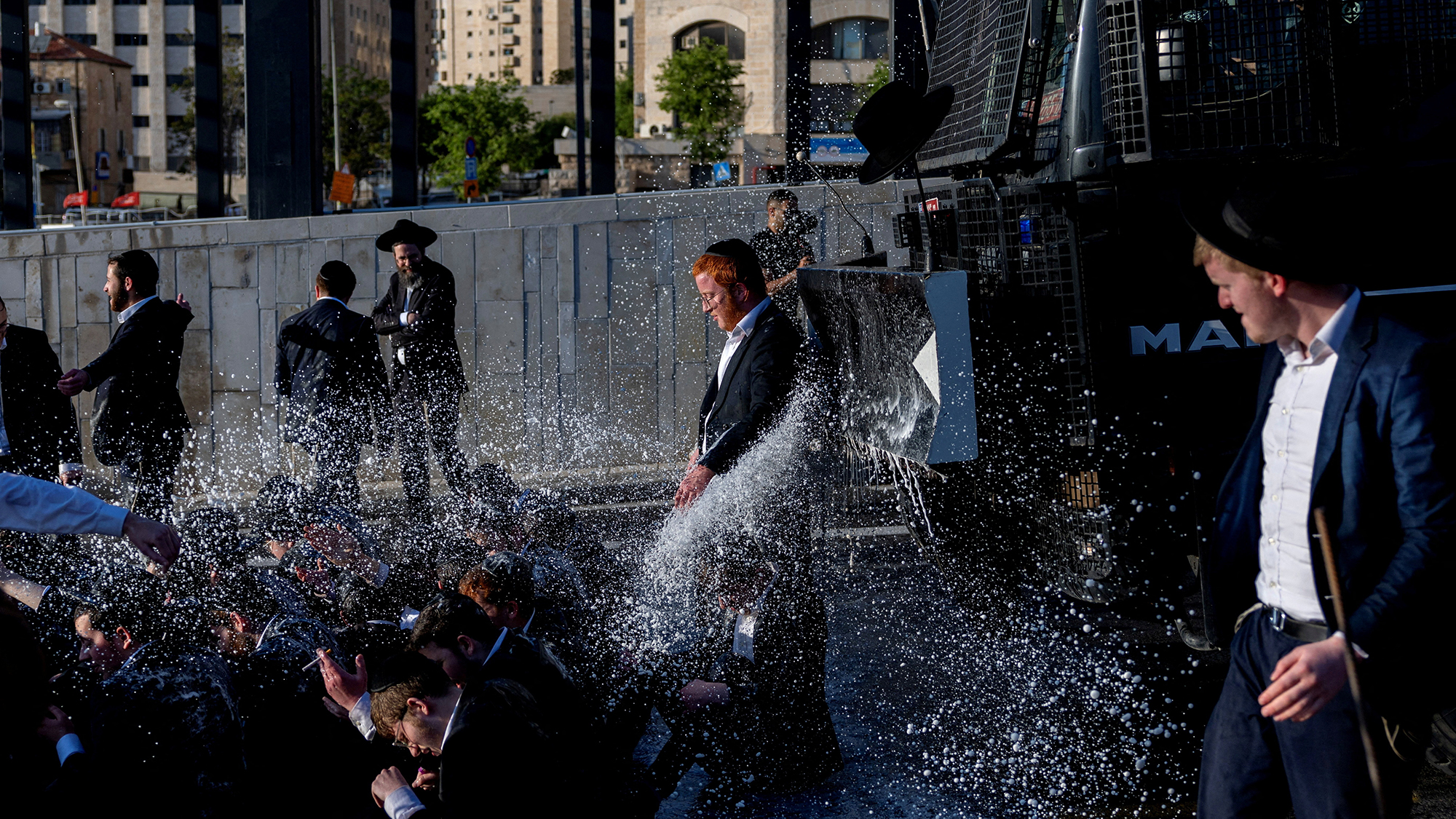 Police spray a group of Ultra-Orthodox Jews with a water cannon during a protest against compulsory military service in Jerusalem, Israel