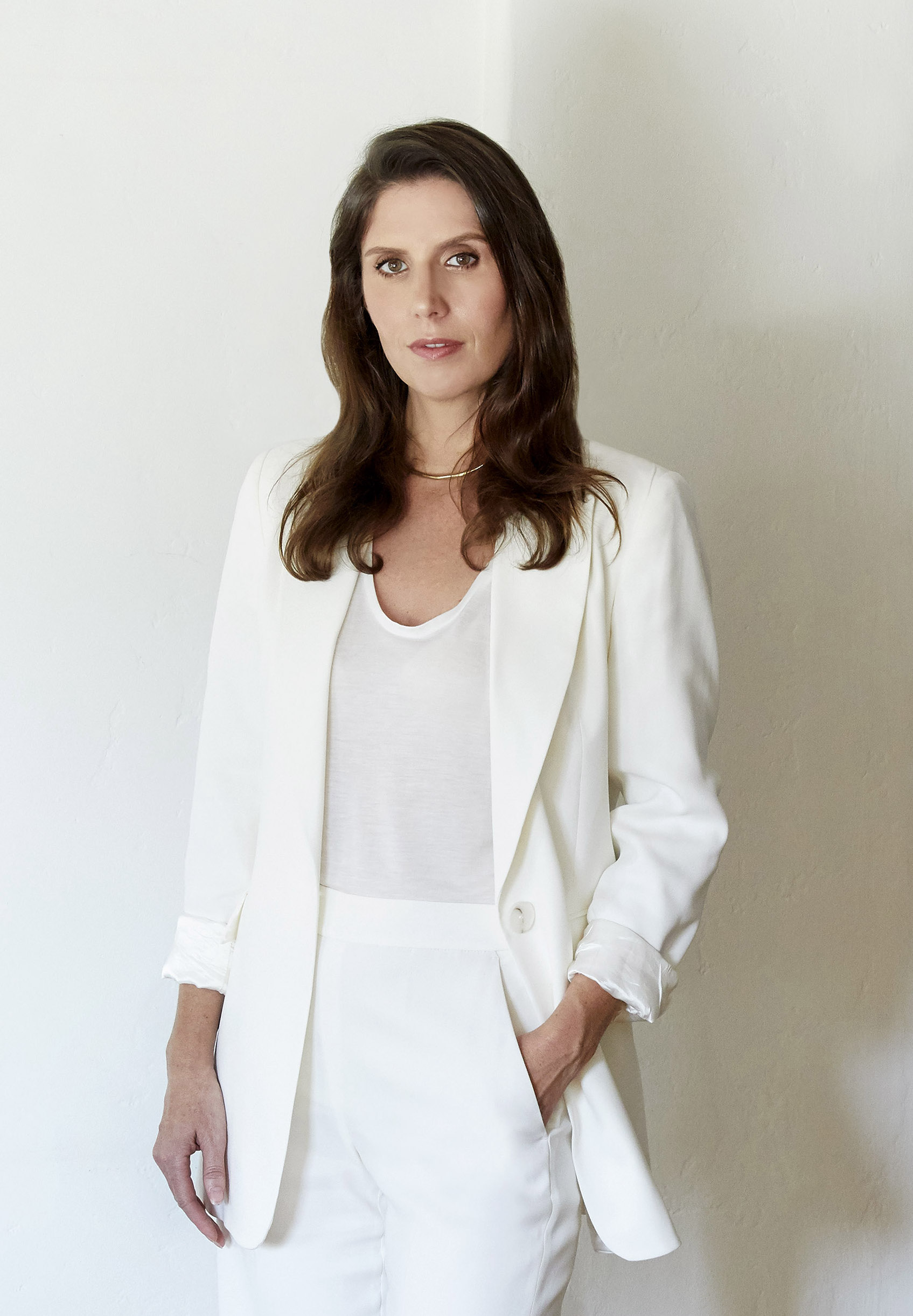 image of interior designer Elizabeth Sims, a woman wearing all white standing in front of white wall with long dark hair
