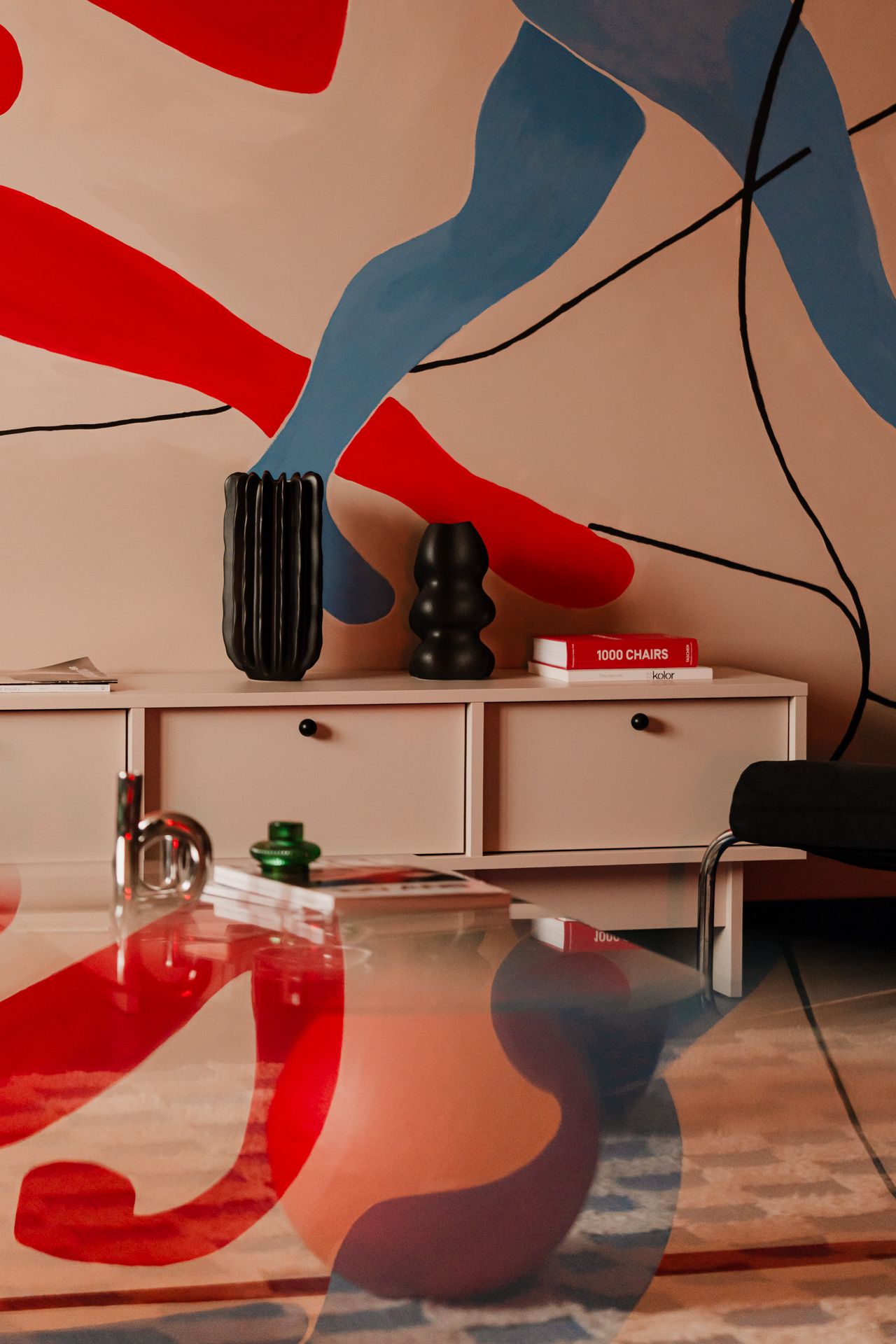 A close-up of a living room mural with red and blue painted figures 'dancing' across the wall.