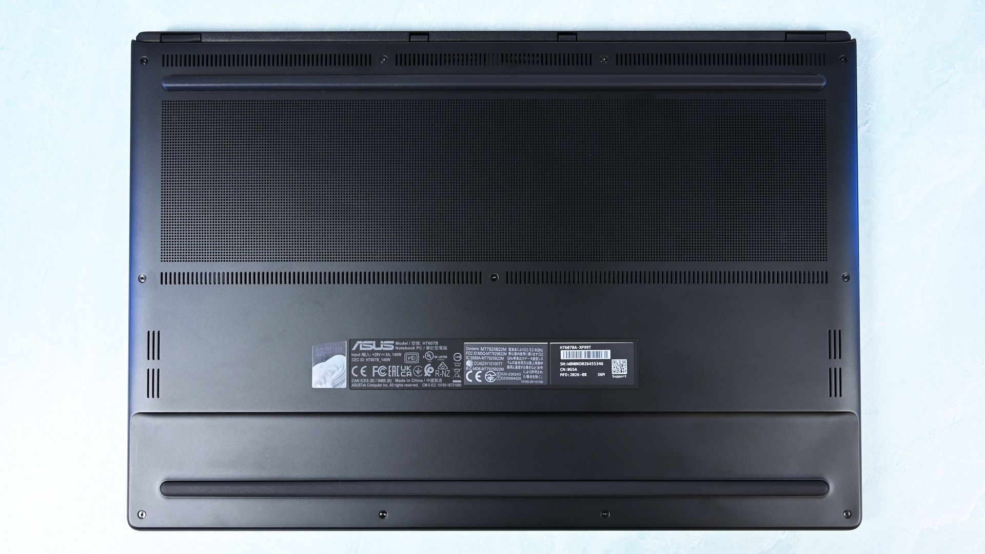 Full bottom chassis view of the ASUS ProArt P16 displaying extensive ventilation grilles, regulatory stickers, speakers, and rubber feet.