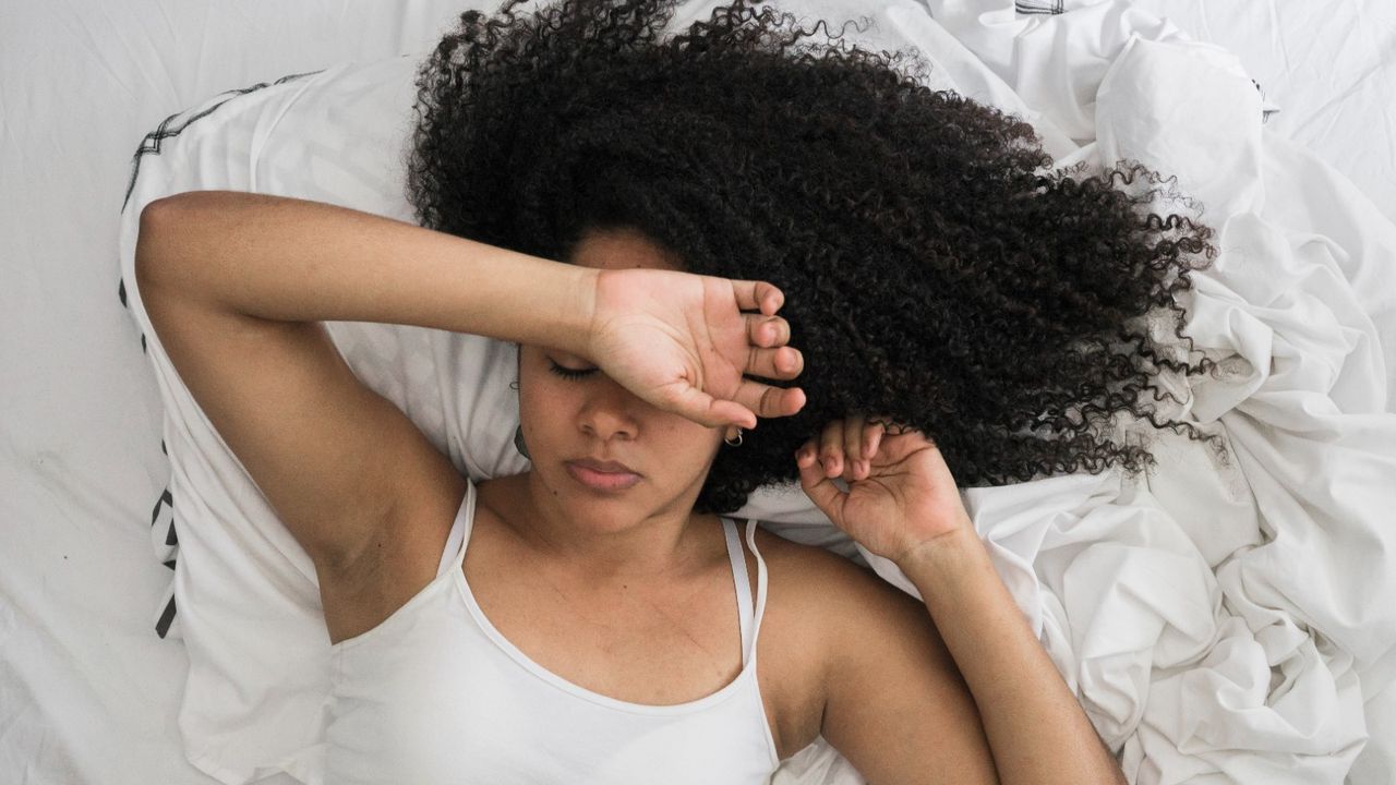 Woman lying on her bed with her arm over her head