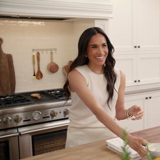 Meghan Markle in cream kitchen smiling at camera