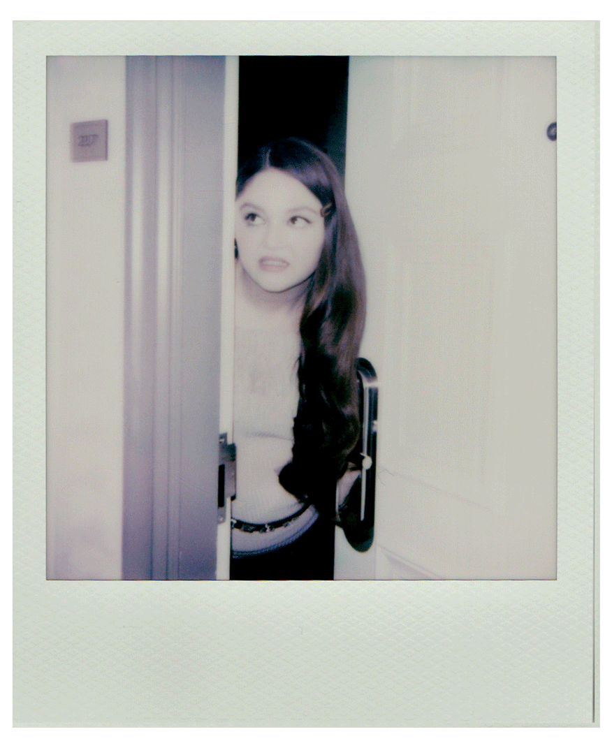 a gif of actress meg stalter in polaroid images peaking through a doorway with her hair over on shoulder