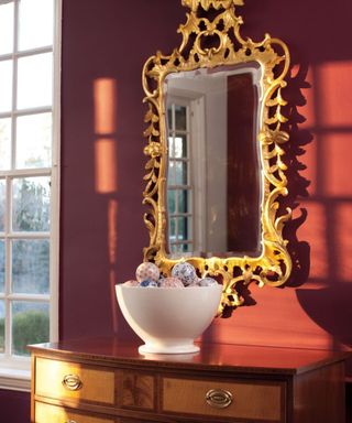 entryway painted in carter plum by benjamin moore with a large antique gilt gold mirror