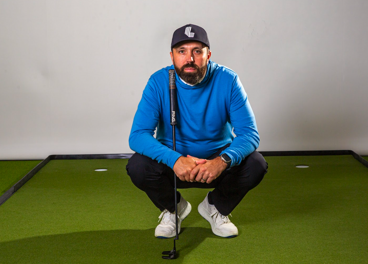 Rick Shiels crouching down wearing a blue hoodie and black cap
