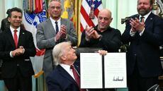 President Donald Trump looks at podcaster Joe Rogan at signing ceremony for hallucinogenics order