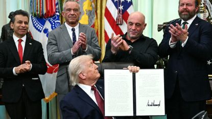 President Donald Trump looks at podcaster Joe Rogan at signing ceremony for hallucinogenics order