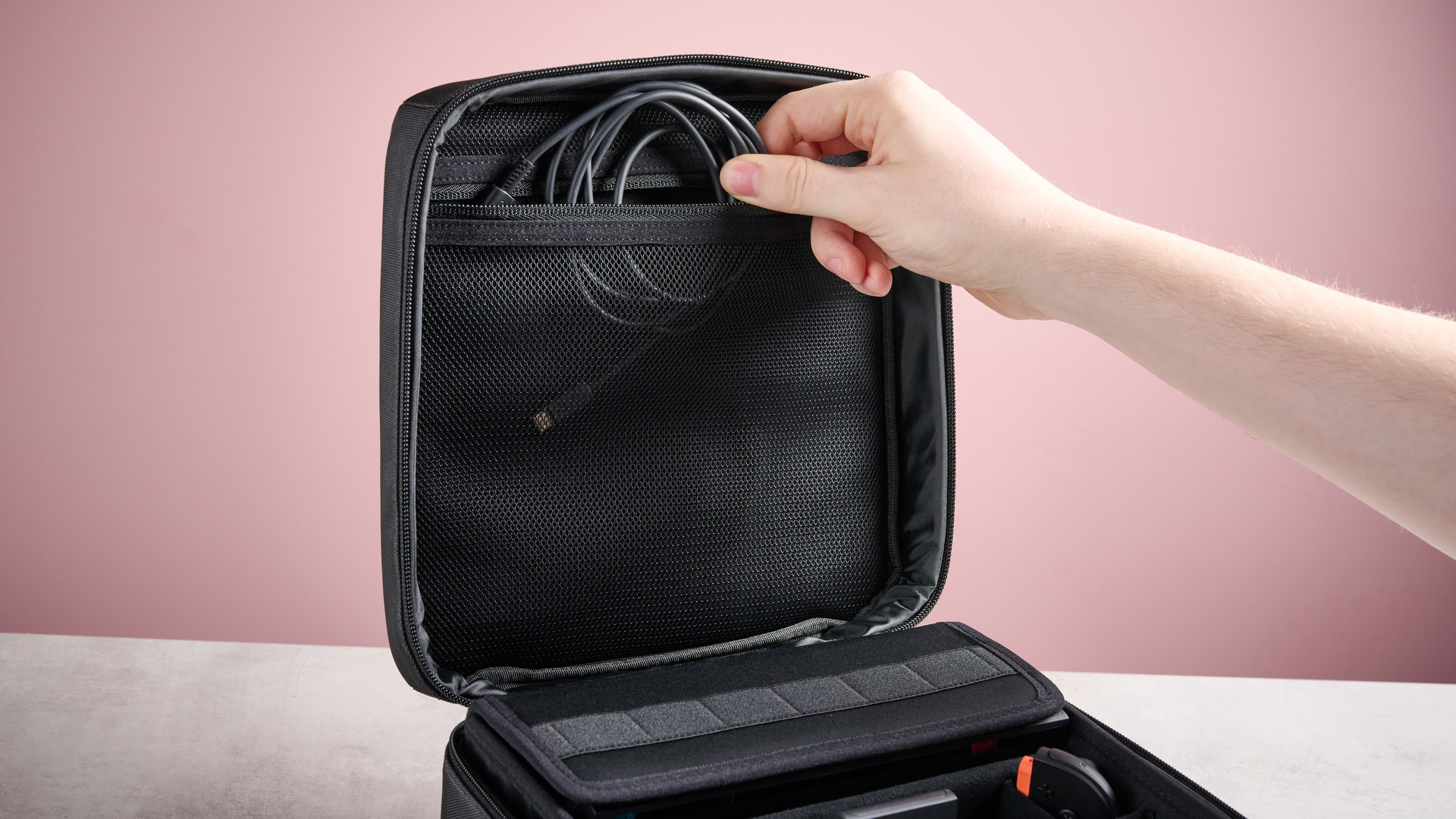 Person placing power cable into the Nintendo Switch 2 All-In-One Carrying Case
