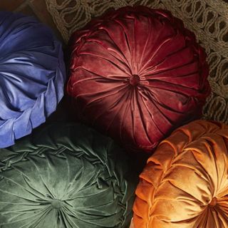 Four round velvet tufted pillows that's a part of Drew Barrymore's furniture collection.