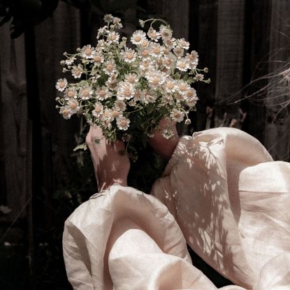 A woman in the shadows; holding a bunch of flowers