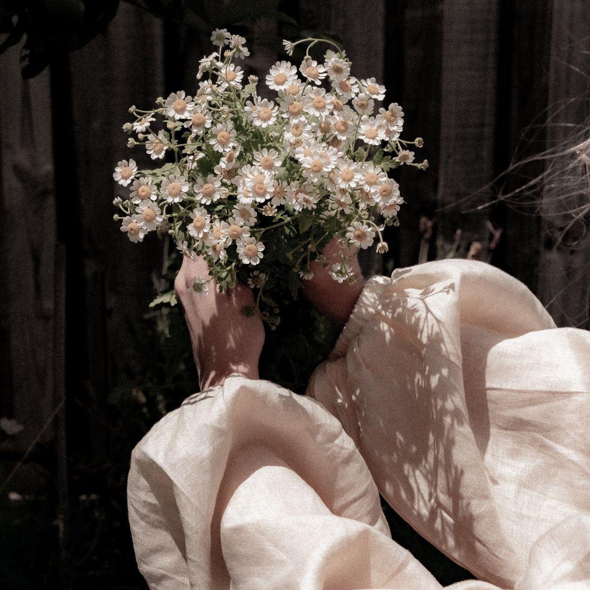 A woman in the shadows; holding a bunch of flowers