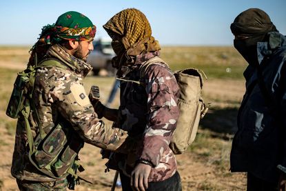 An SDF fighter searches a suspected ISIS fighter.