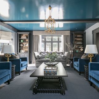 living room with moody grey textured walls and exposed brick walls and a glossy blue ceiling bespoke coffee table and azure blue arm chairs
