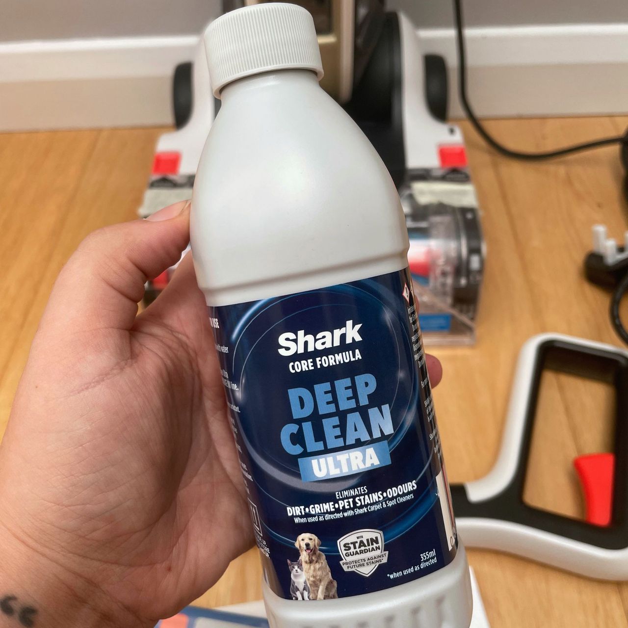 hand holding a bottle of the cleaning solution of the Shark CarpetForce Upright Carpet Cleaner