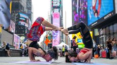 Two people do an elaborate yoga pose in Times Square