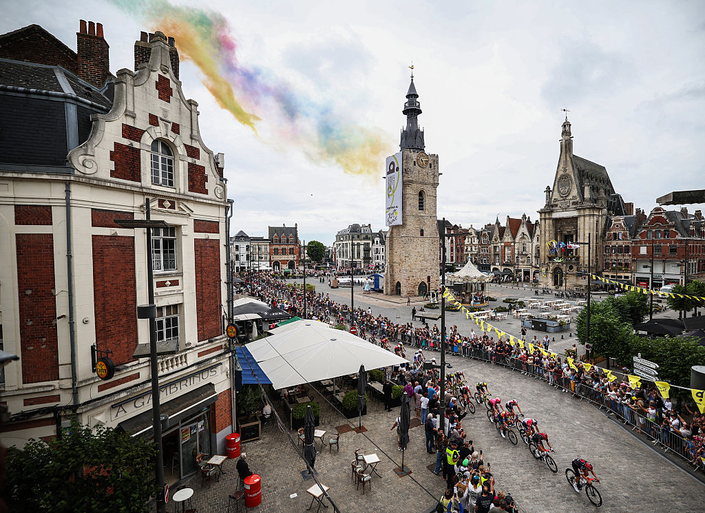 The pack of riders (peloton) cycles through the town of Bethune during the 1st stage of the 112th edition of the Tour de France cycling race, 184.9 km starting and finishing in Lille Metropole, northern France, on July 5, 2025. (Photo by Anne-Christine POUJOULAT / AFP)