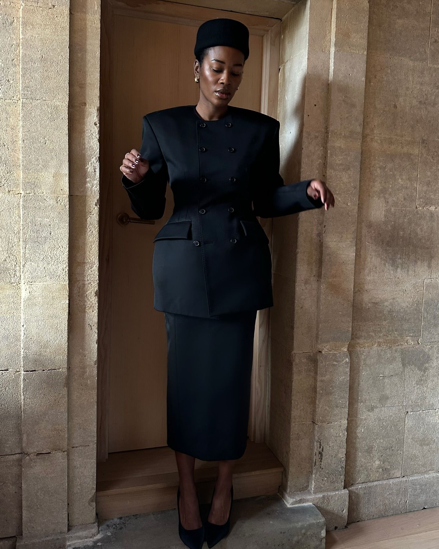 Influencer @nlmarilyn wears a black Wardrobe.NYC dress with a black column skirt and a black pillar hat.