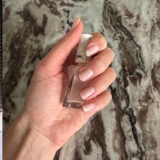 A hand holding a bottle of essie nail polish