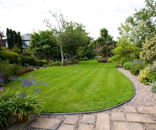 large lawn with curved edge and flagged patio with gravel path