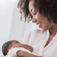 postpartum hair loss - Close up portrait of beautiful young African American mother holding newborn baby - gettyimages 1415734991