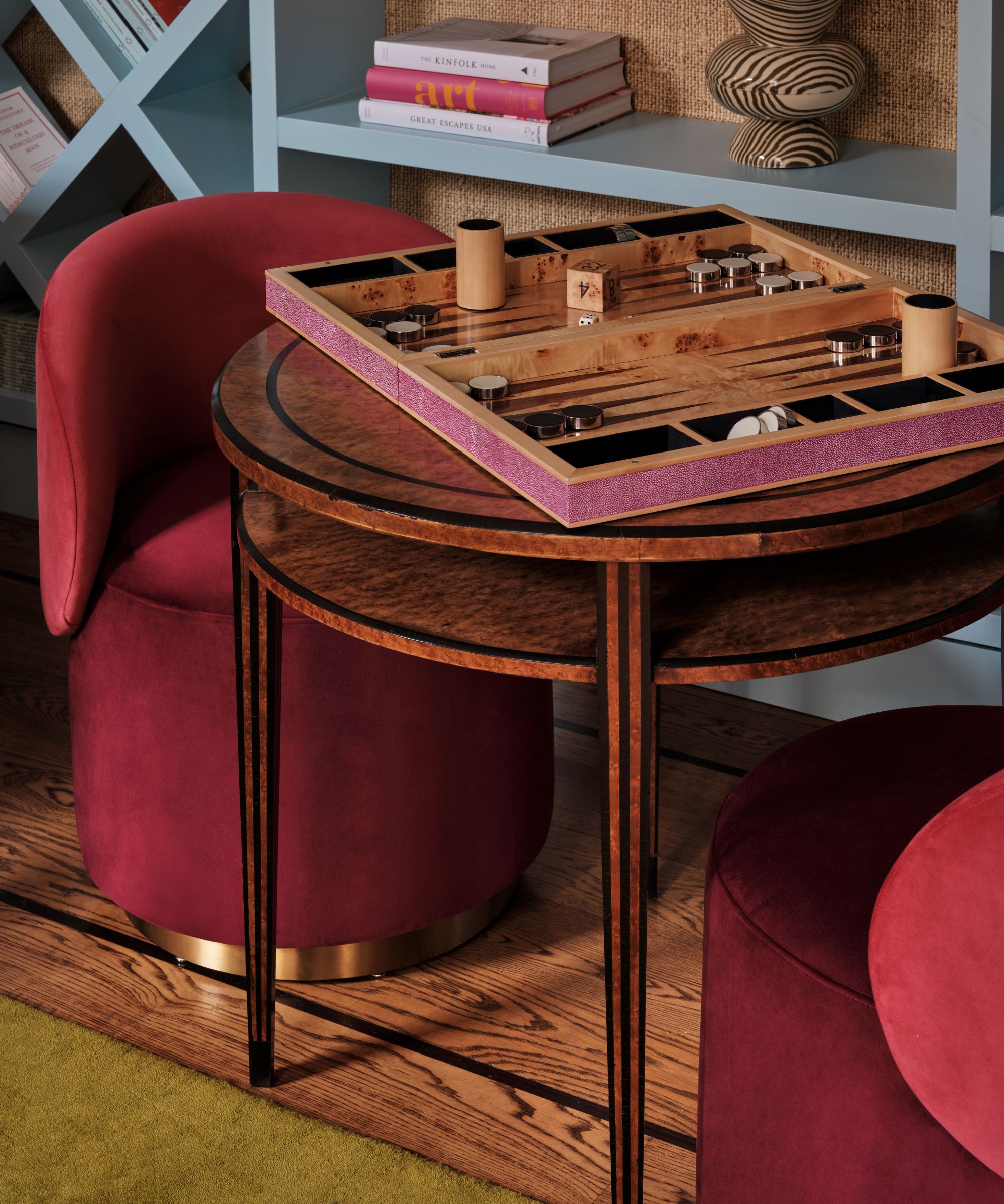 a close up shot of a small antique games table with dark pink velvet chairs