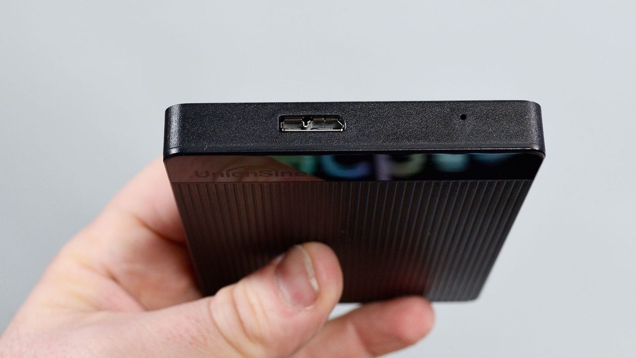 A masculine hand holding a UnionSine Ultra Slim external HDD