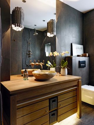 wooden vanity in a black spa bathroom with stone basin on top