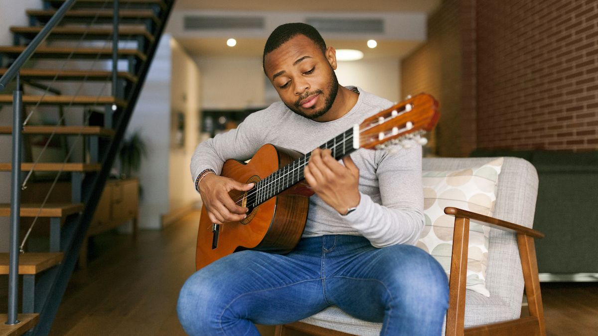 Man playing a classical guitar at the bottom of some stairs