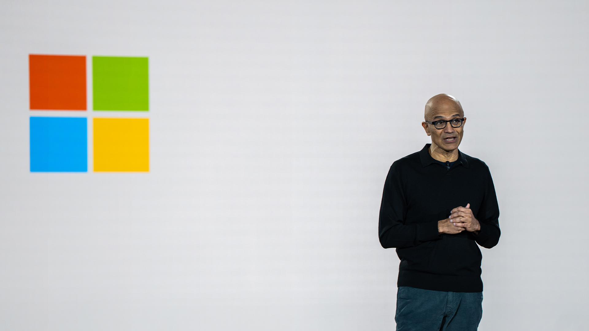 Microsoft CEO Satya Nadella pictured on stage at the Microsoft 50th Anniversary event in Redmond, Washington, with the company logo on a screen to his right.
