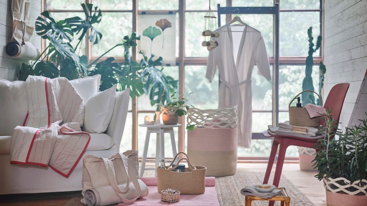 items in the IKEA VÅRDANDE collection, such as a bag, plant pot and blanket, in a light bright living space with huge black crittall windows, a white sofa and a large plant