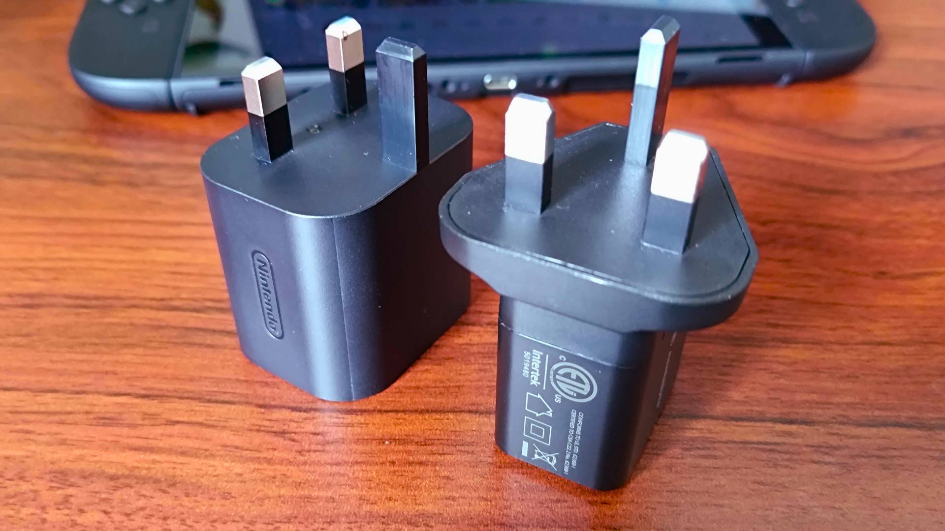 Nintendo Switch 2 charger next to third-party SnakeByte alternative on desk.