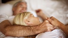 Couple holding hands in bed