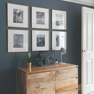 A living room painted in navy with a photo gallery wall displayed above a sideboard