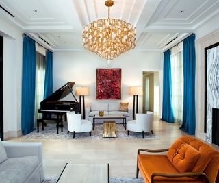 Orange armchair, blue curtains, piano, chandelier