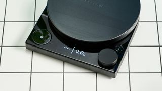 fellow tally pro coffee scale with a large circular weighing pad and coffee beans and an LED display with a dial and timer photographed against a blue tom's guide background