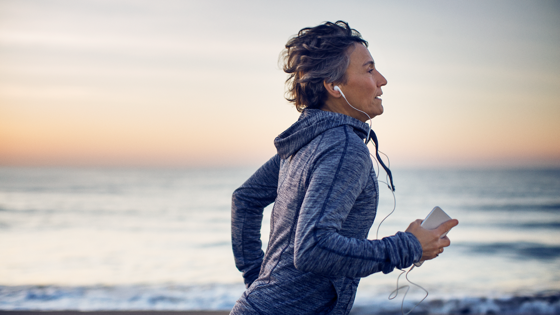 Woman running along beach with headphones