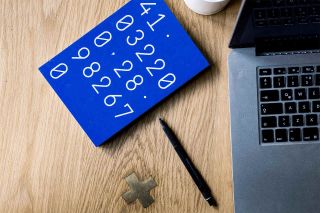 Blue tablet computer displays large numbers next to open laptop.