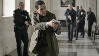 Ramón Rodríguez as Will Trent holding a gun with cops behind him in Will Trent