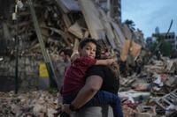 People walk past a collapsed building following an earthquake in Caracas on June 25, 2026. Powerful twin earthquakes have killed 32 people and injured more than 700, the nation's interim president said on June 25, after the massive shocks collapsed entire buildings and sent people running in panic. (Photo by Manaure QUINTERO / AFP)