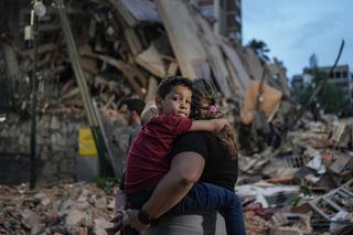 People walk past a collapsed building following an earthquake in Caracas on June 25, 2026. Powerful twin earthquakes have killed 32 people and injured more than 700, the nation's interim president said on June 25, after the massive shocks collapsed entire buildings and sent people running in panic. (Photo by Manaure QUINTERO / AFP)