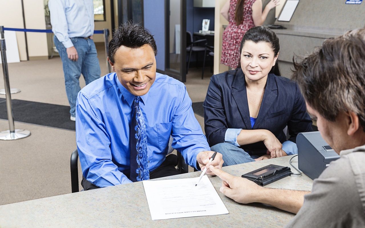 A mature couple receives an application at a bank.