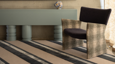 A striped carpet with a baby blue console table and a stylish lounge chair